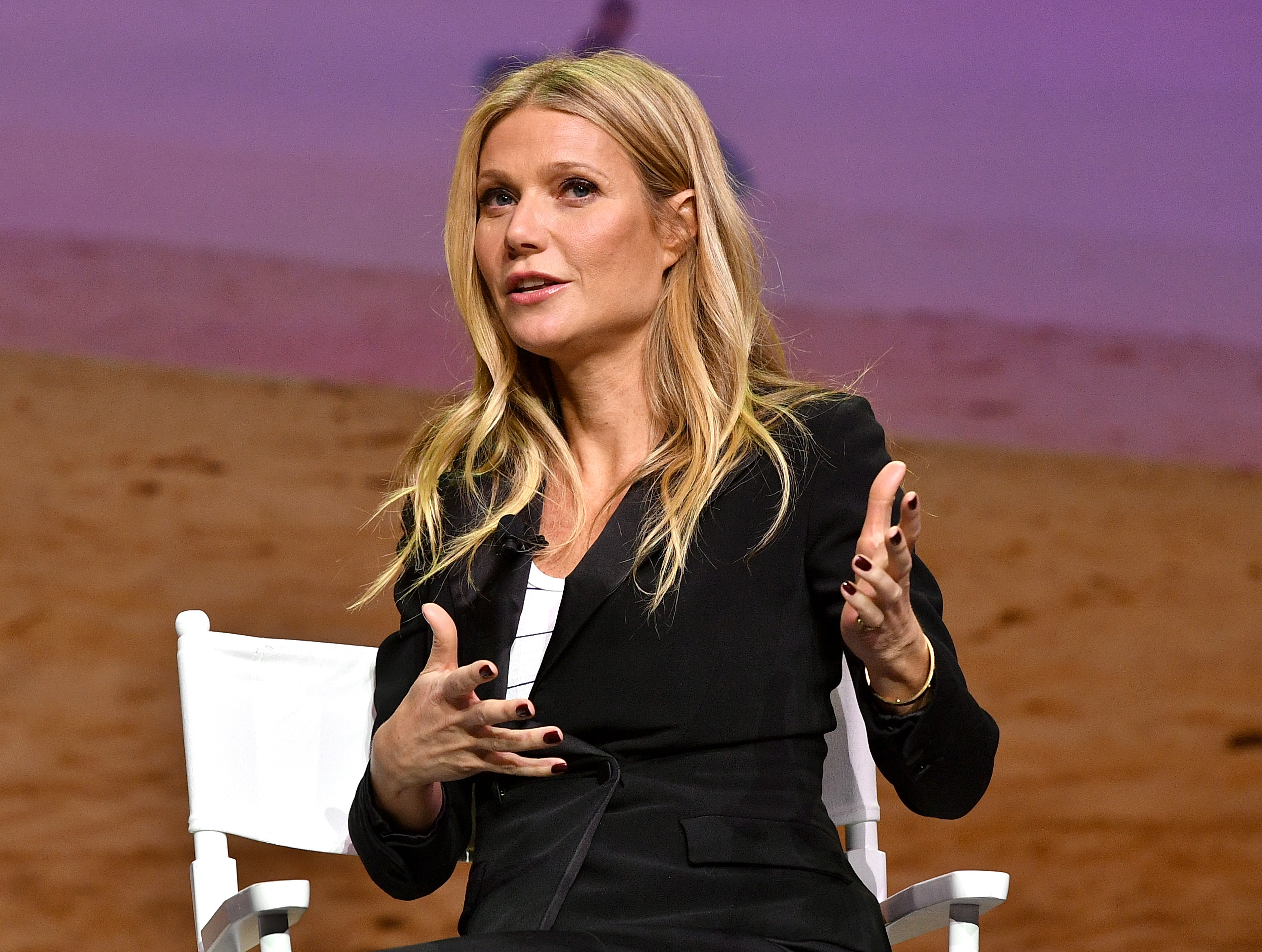 Gwyneth Paltrow sitting in a white chair while gesturing